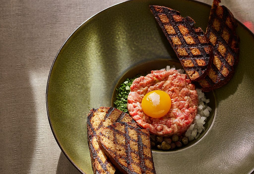 Steak tartare plated with egg and toast